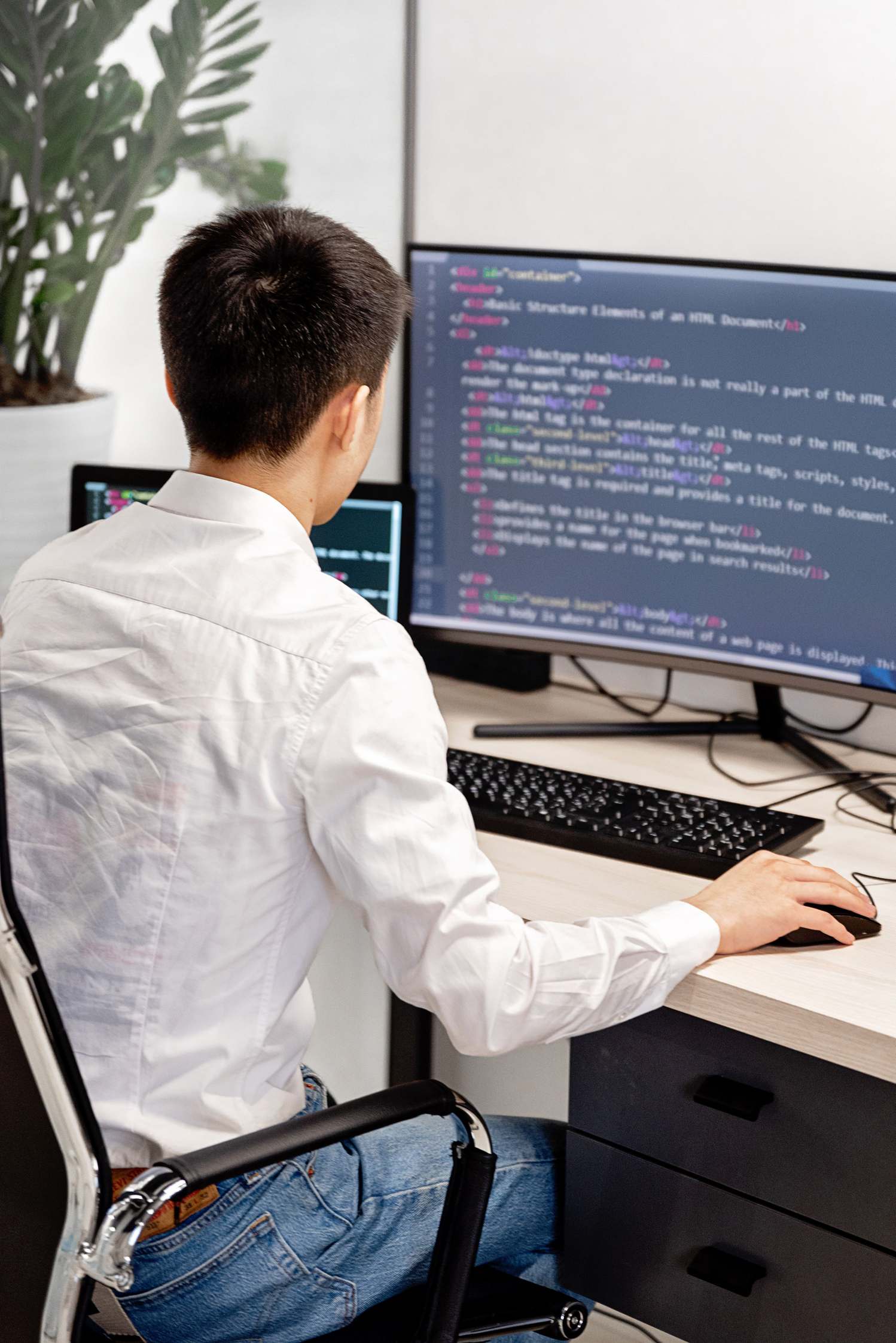 Software developer workspace with monitors on a desk, in a well-lit home office setup